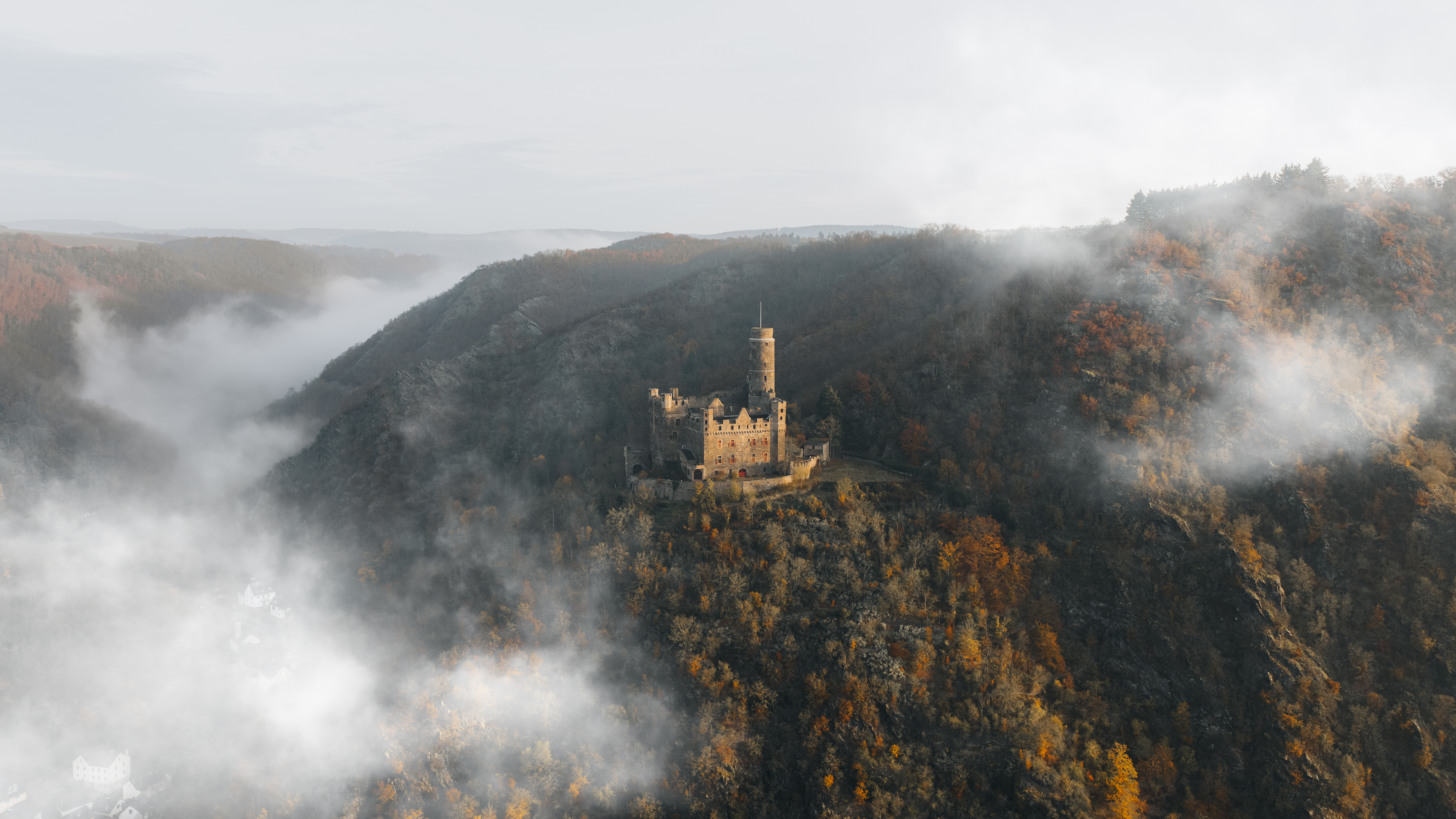 Burg im Nebel auf einem Hügel